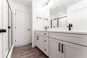 Bathroom featuring hardwood / wood-style flooring, a shower with shower door, and vanity