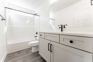 Full bathroom featuring hardwood / wood-style flooring, vanity, toilet, and  shower combination