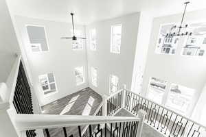 Stairs with a high ceiling, hardwood / wood-style floors, and ceiling fan with notable chandelier