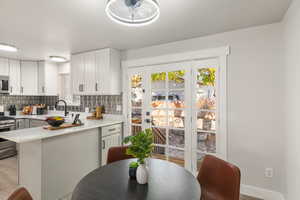 Kitchen featuring sink, decorative backsplash, white cabinets, and stainless steel appliances