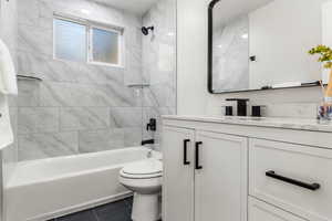 Full bathroom featuring tiled shower / bath, vanity, toilet, and tile patterned flooring