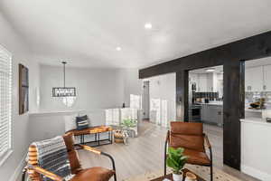 Living room with light hardwood / wood-style floors and a notable chandelier