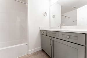 Bathroom with shower / tub combination, a textured ceiling, wood-type flooring, and vanity