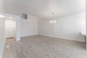 Spare room featuring a notable chandelier and light hardwood / wood-style floors