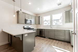 Kitchen featuring stainless steel appliances, pendant lighting, a breakfast bar, sink, and kitchen peninsula