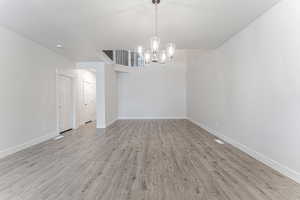 Empty room featuring light hardwood / wood-style flooring and a notable chandelier