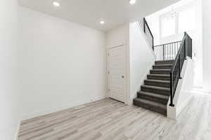 Staircase with hardwood / wood-style floors and a chandelier