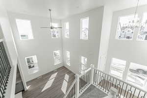 Interior space featuring ceiling fan with notable chandelier, dark hardwood / wood-style floors, and a towering ceiling