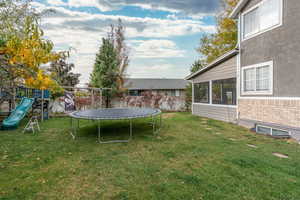 View of yard featuring a playground, a trampoline, and a sunroom