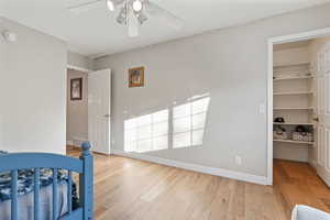 Bedroom featuring a spacious closet, a closet, light wood-type flooring, and ceiling fan