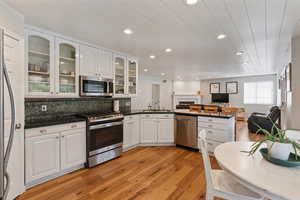 Kitchen with light hardwood / wood-style flooring, kitchen peninsula, white cabinets, and stainless steel appliances