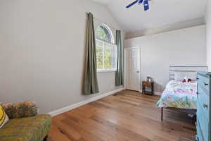 Bedroom with light hardwood / wood-style floors, vaulted ceiling, and ceiling fan