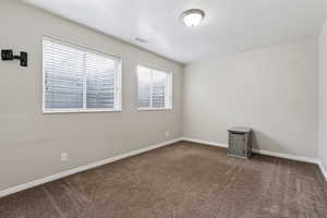 Spare room featuring dark colored carpet