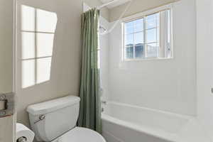 Bathroom with shower / bath combination with curtain and toilet