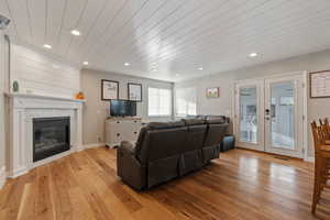 Living room featuring french doors, light hardwood / wood-style flooring, wood ceiling, and a fireplace