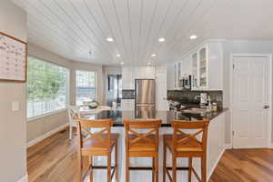 Kitchen featuring appliances with stainless steel finishes, kitchen peninsula, white cabinetry, and light wood-type flooring