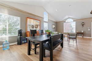 Dining space with light hardwood / wood-style floors and vaulted ceiling