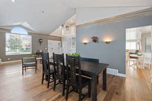 Dining area featuring vaulted ceiling, wood-type flooring, and plenty of natural light