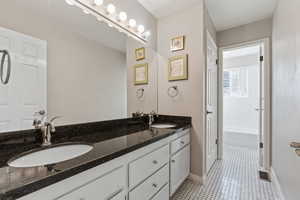 Bathroom with vanity, tile patterned flooring, and a washtub