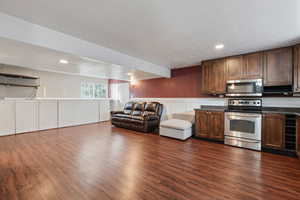 Kitchen with appliances with stainless steel finishes, a textured ceiling, beverage cooler, and dark wood-type flooring