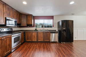 Kitchen featuring dark wood-type flooring, stainless steel appliances, sink, and a textured ceiling