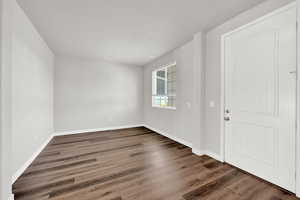 Empty room featuring dark hardwood / wood-style flooring