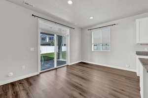 Unfurnished dining area with wood-type flooring and a textured ceiling