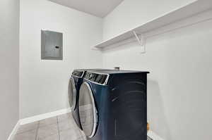 Laundry room featuring washer and dryer, electric panel, and light tile patterned floors