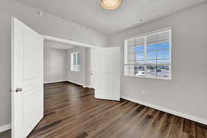 Spare room with a textured ceiling and dark wood-type flooring