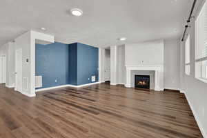 Unfurnished living room featuring a textured ceiling, dark hardwood / wood-style flooring, a tile fireplace, and a barn door