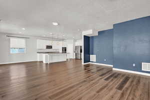 Unfurnished living room with a textured ceiling, sink, and dark hardwood / wood-style flooring