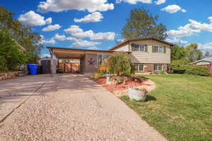 Tri-level home with a carport, a front yard, and a shed