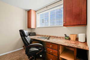 Home office featuring built in desk and carpet