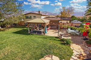 Rear view of house featuring a gazebo, an outdoor living space, a yard, a patio area, and a mountain view