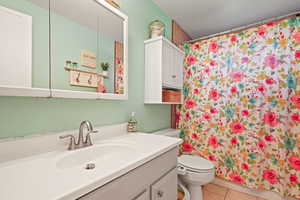 Bathroom featuring walk in shower, vanity, toilet, and tile patterned floors