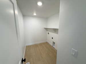 Clothes washing area featuring hookup for a washing machine, light hardwood / wood-style floors, and hookup for an electric dryer