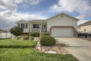 View of front of house featuring a garage, a front lawn, and a porch