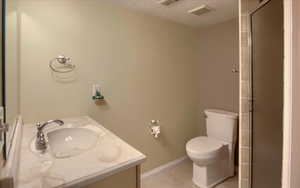 Bathroom with tile patterned flooring, vanity, toilet, and a textured ceiling