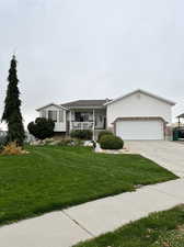 Ranch-style house featuring a front yard, a garage, and a porch