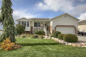 View of front of house with a front lawn, a garage, and covered porch