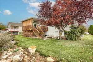 Rear view of house featuring a lawn and a wooden deck