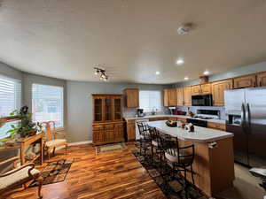 Kitchen featuring white appliances, a kitchen island, a kitchen breakfast bar, hardwood / wood-style flooring, and decorative backsplash