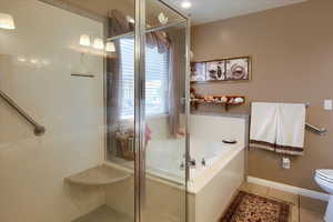 Bathroom with toilet, shower with separate bathtub, and tile patterned floors