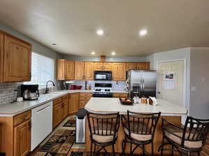 Kitchen with a center island, sink, backsplash, and white appliances