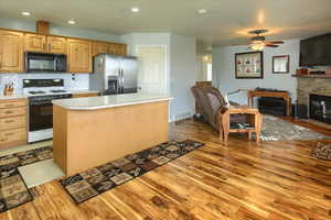 Kitchen featuring white gas stove, ceiling fan, light hardwood / wood-style flooring, a center island, and stainless steel fridge