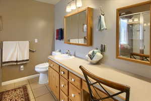 Bathroom featuring vanity, a shower with shower door, tile patterned floors, and toilet