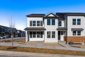 View of front of home featuring cooling unit, brick siding, and board and batten siding