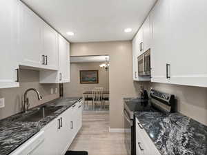 Kitchen with light hardwood / wood-style flooring, white cabinetry, stainless steel appliances, and sink