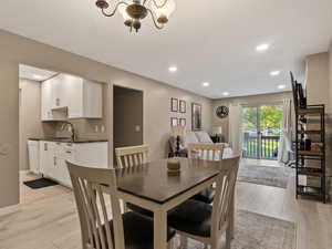 Dining room with an inviting chandelier, sink, and light wood-type flooring