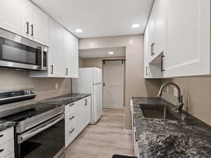 Kitchen featuring appliances with stainless steel finishes, sink, a barn door, and white cabinets